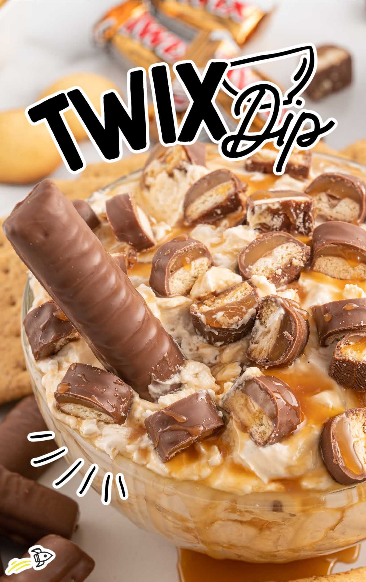 a close up shot of Twix Dip with a Twix being dipped in it