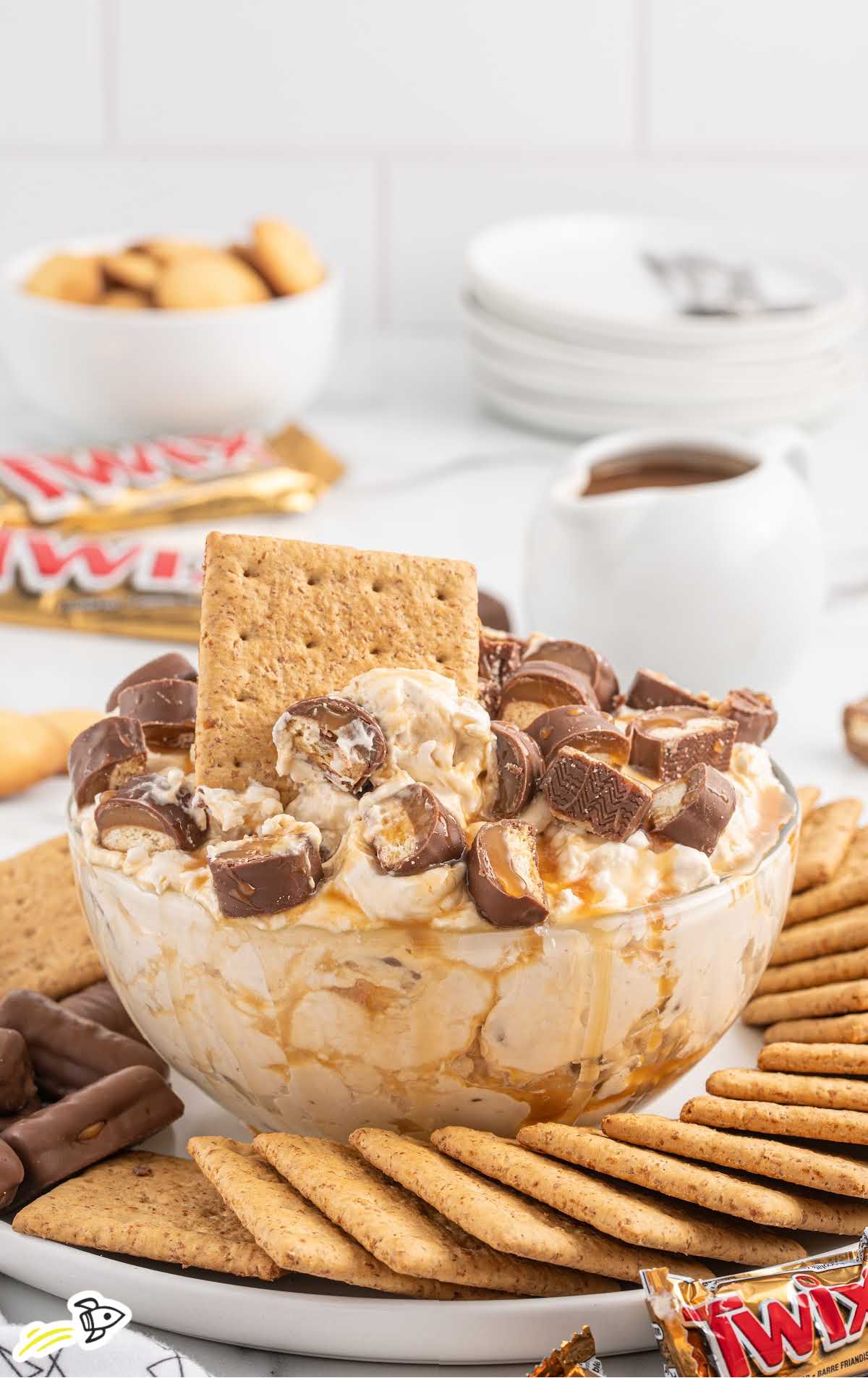 a close up shot of Twix Dip with a cracker being dipped in it