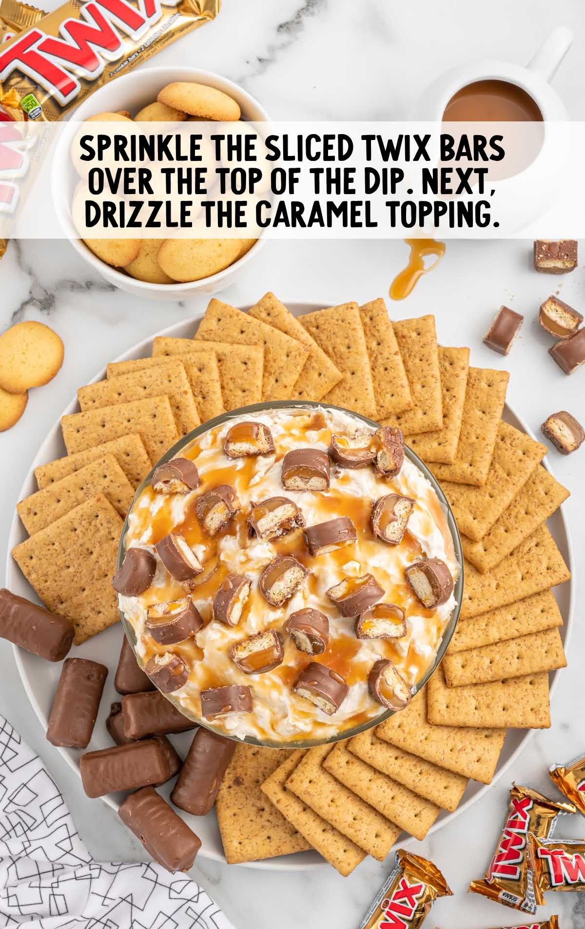 twix bars sprinkled over the top of the dip as well as caramel dip