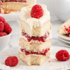 a close up shot of a slice of White Chocolate Raspberry Cake on a plate