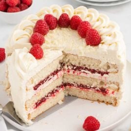 a close up shot of White Chocolate Raspberry Cake with a slice taken out