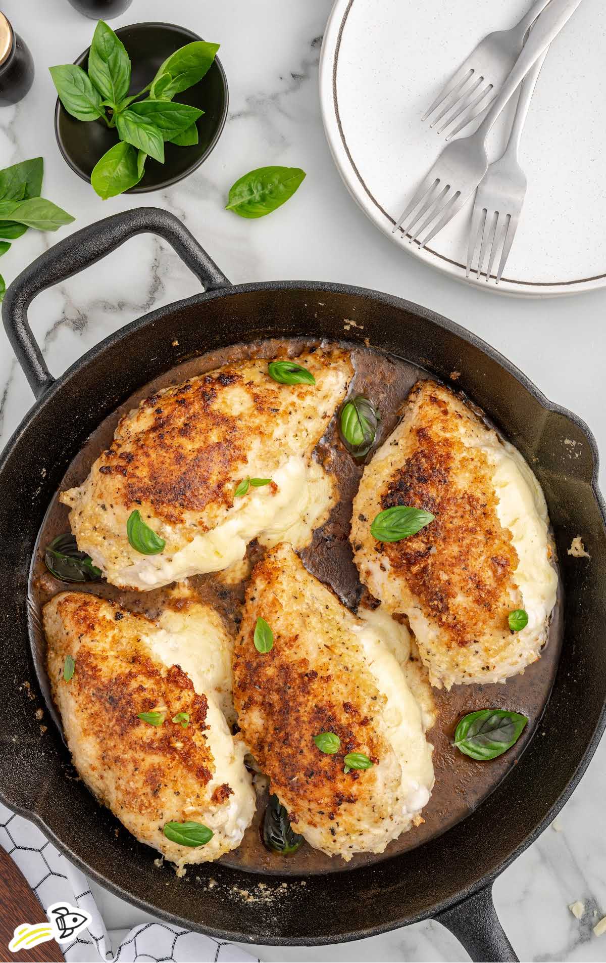 Cheese Stuffed Chicken Breasts garnished with basil in a skillet