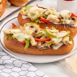 a close up shot of a couple of Chicken Cheesesteaks on a plate