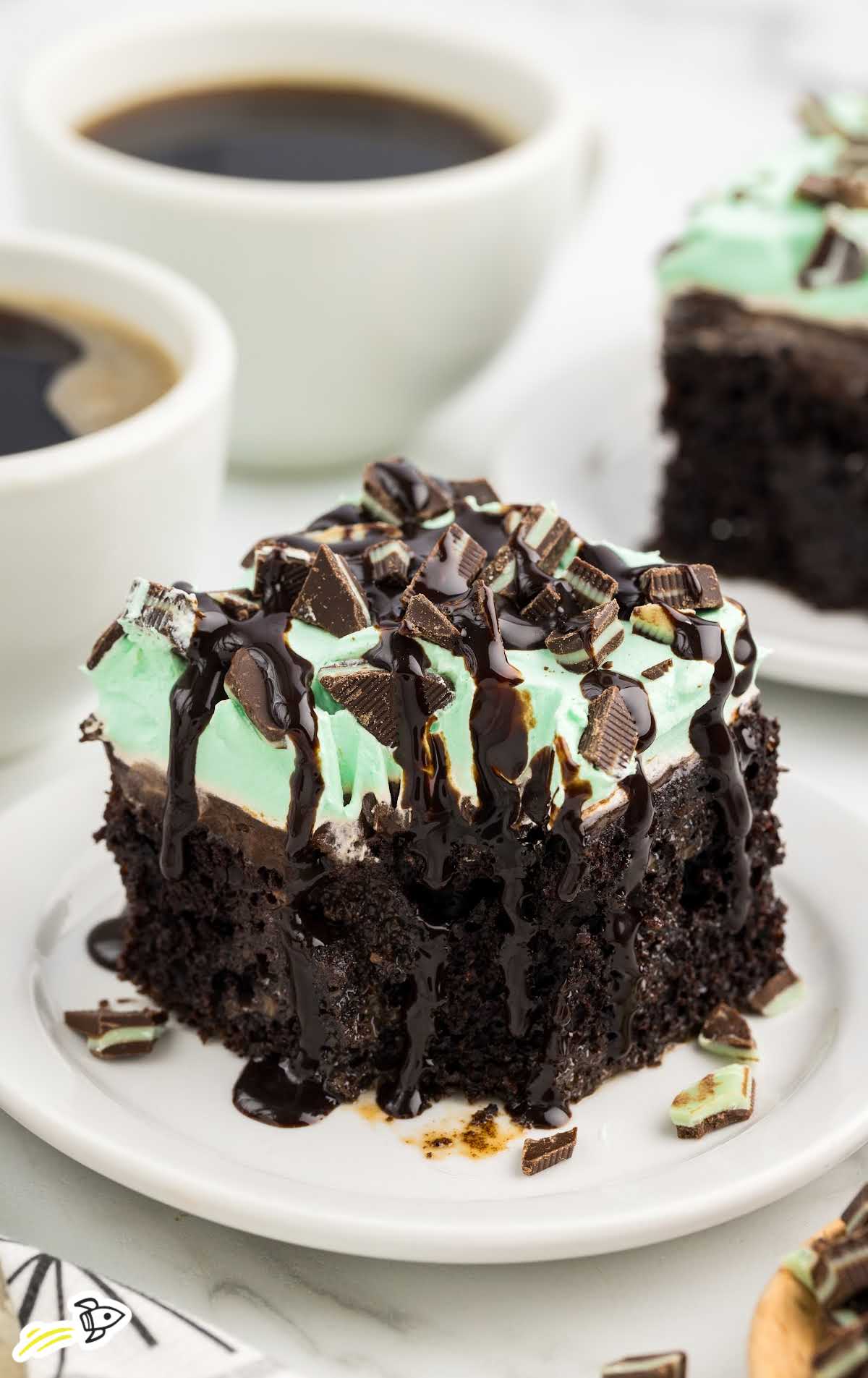 a slice of cake topped with mint chocolate candies and drizzled with chocolate syrup on a plate