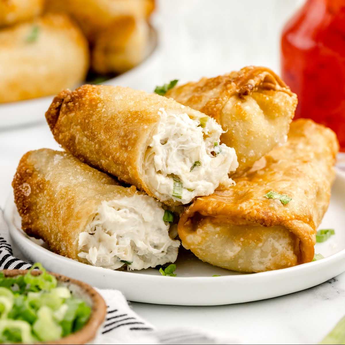 close up shot of Crab Rangoon Eggrolls stacked on top of each other on a plate