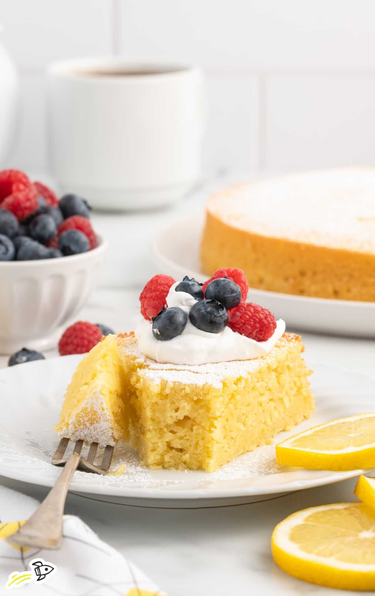 a slice of Italian Lemon Cake topped with whipped cream and berries on a plate with a fork