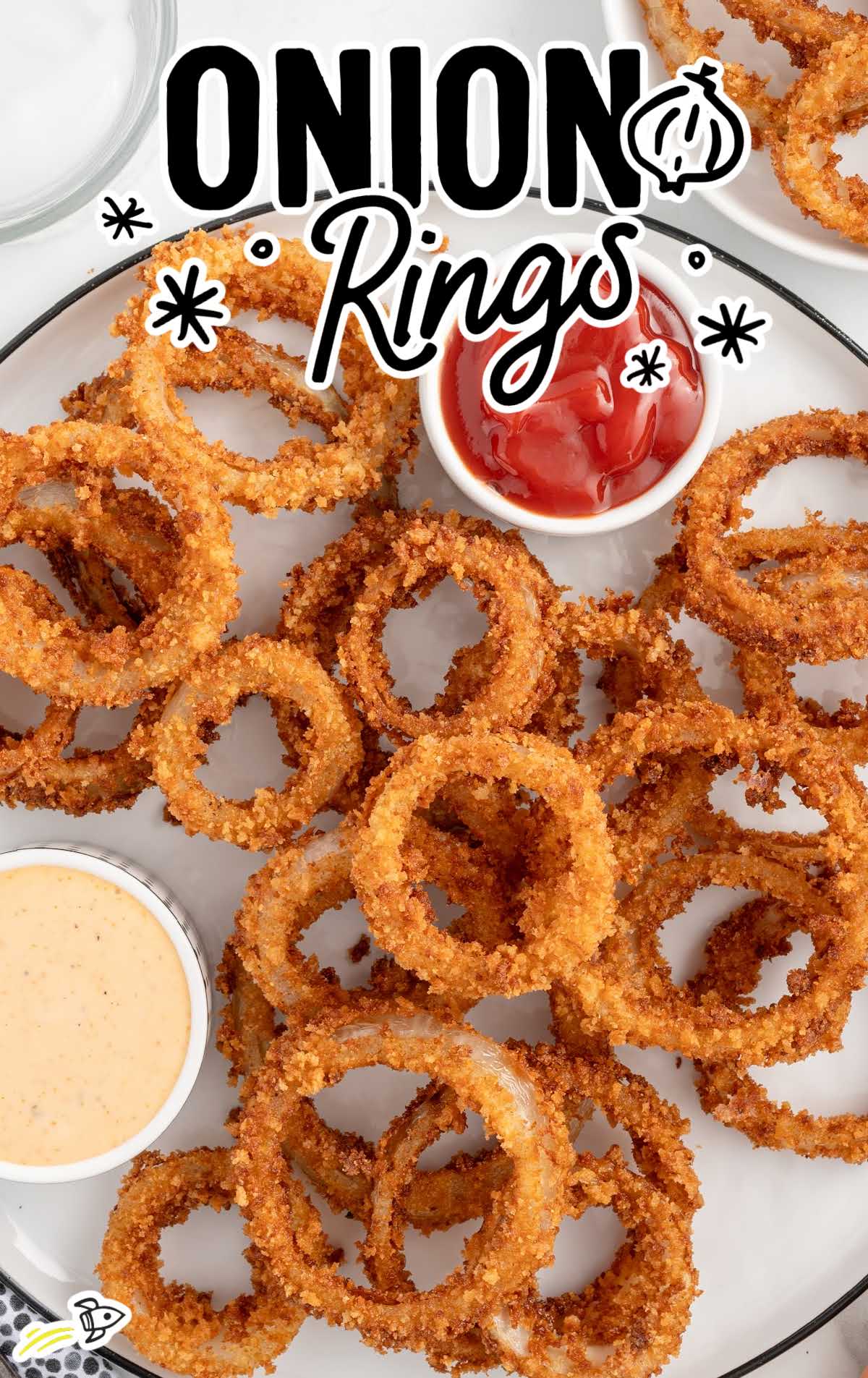 Top view of crunchy onion rings with ketchup and spicy dipping sauce