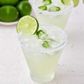 glasses of Spicy Margarita garnished with slices of lime and jalapeños