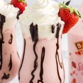 close up shot of glasses of Strawberry Mudslide topped with chocolate sauce, whipped cream, and a strawberry