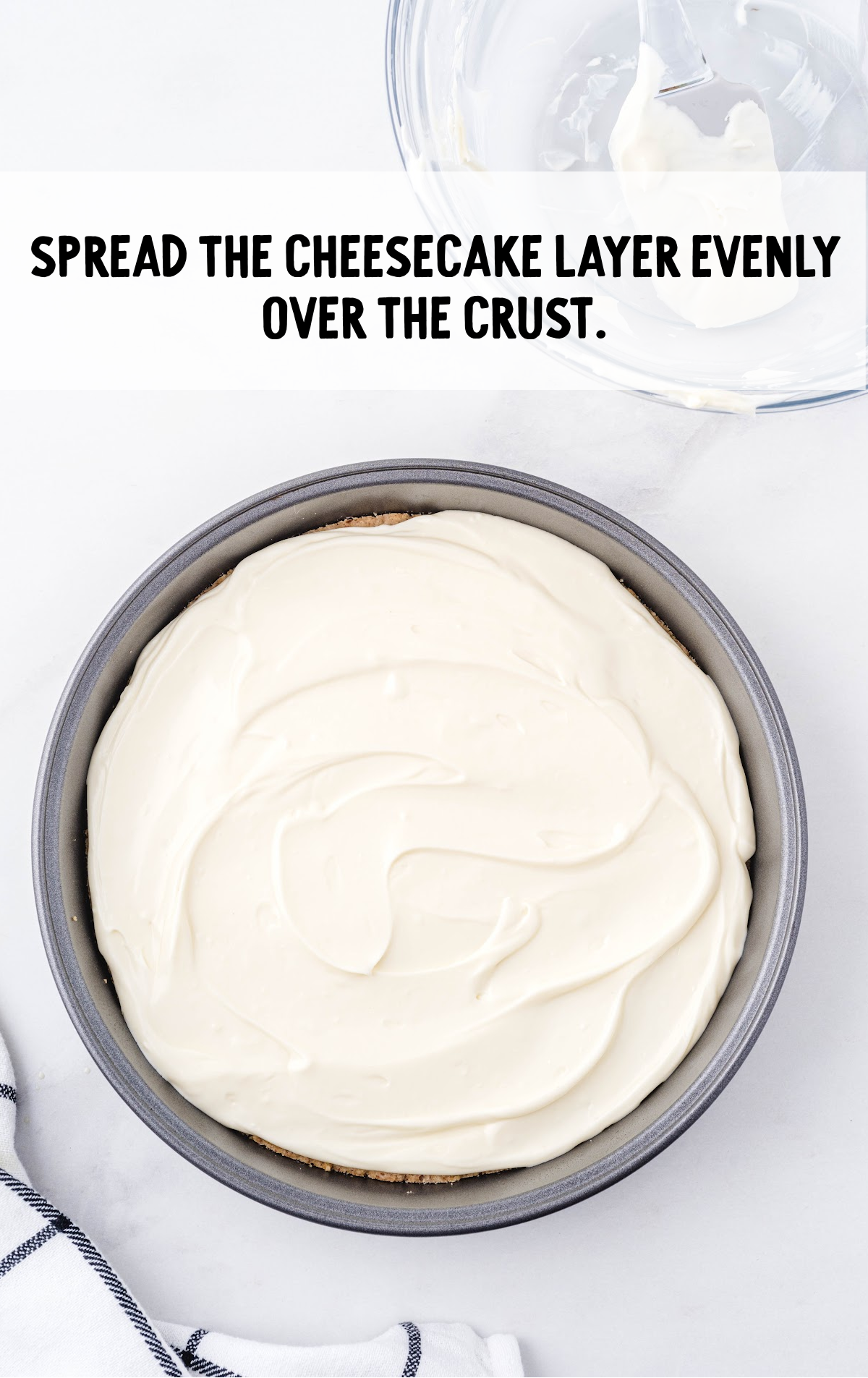 cheesecake layer spread evenly over crust in a pan