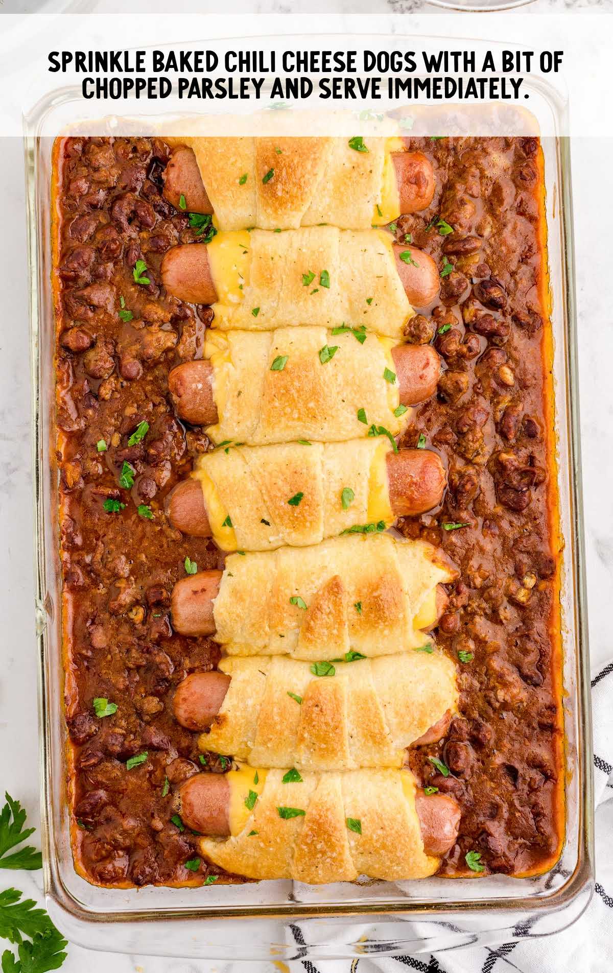chili cheese dog bake sprinkled with parsley in a baking dish