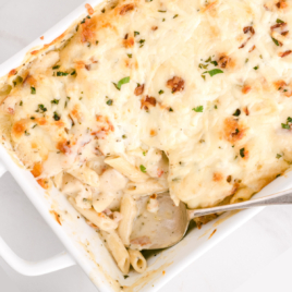 An overhead view of a pan of chicken bacon ranch casserole with a scoop of pasta scooped out of it.