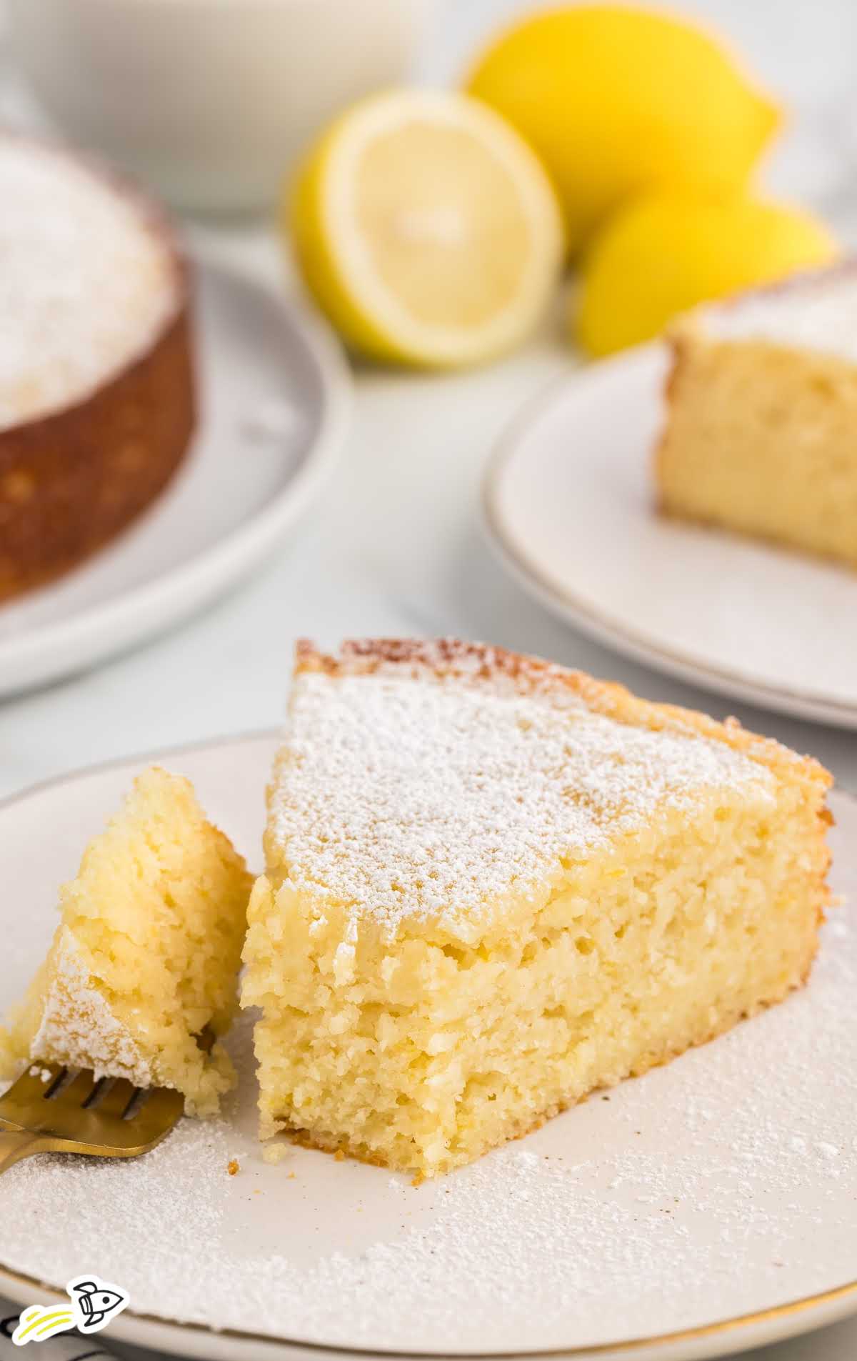 close up shot of a slice of Lemon Ricotta Cake on a plate with a piece taken out of it