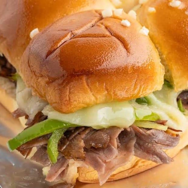 Baked Philly cheesesteak sliders with sliced steak, green peppers, onions, and melted provolone