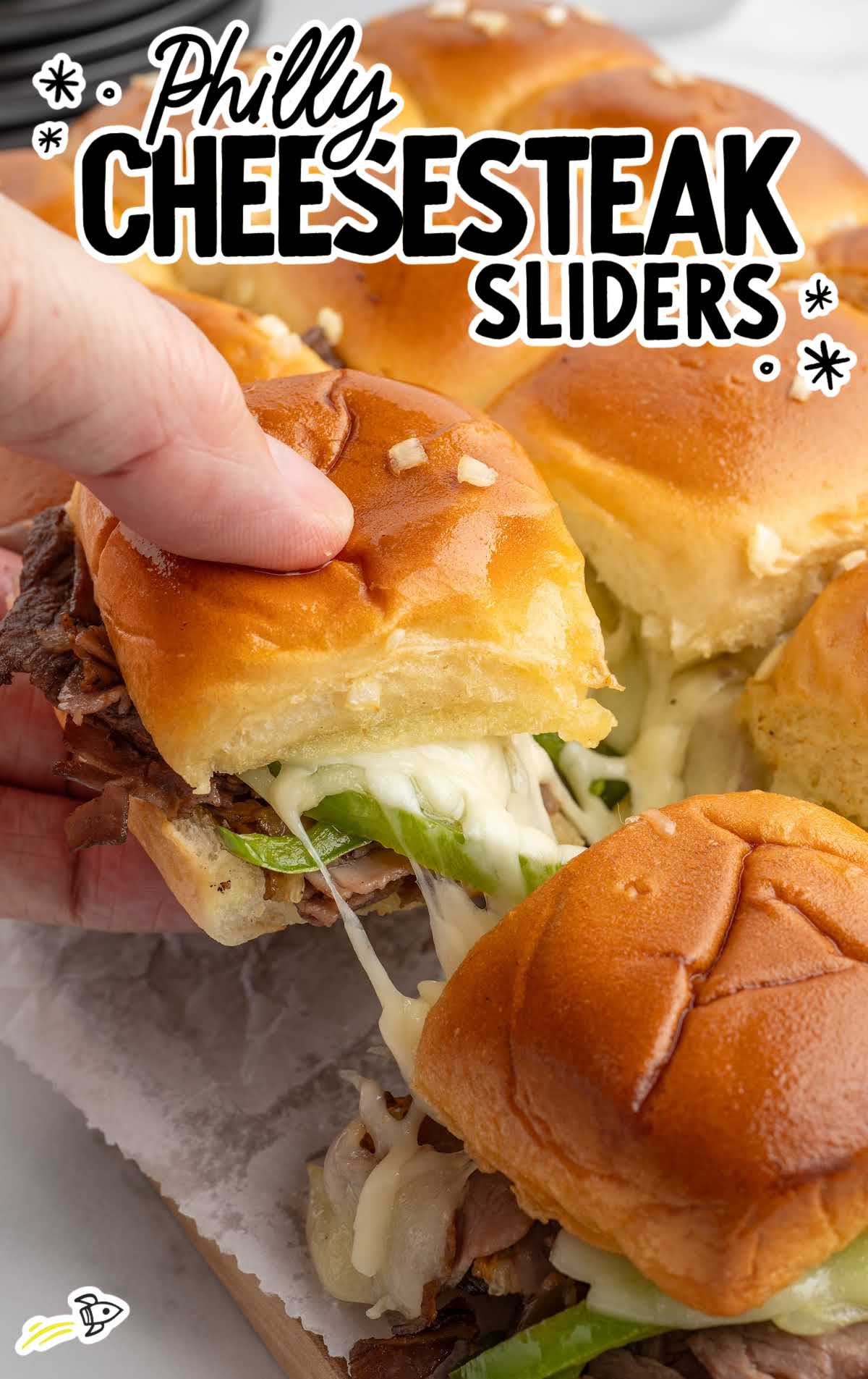 Close-up of a Philly cheesesteak slider being pulled apart with melted provolone cheese