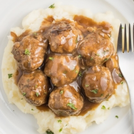 a dinner plate of mashed potatoes and meatballs.