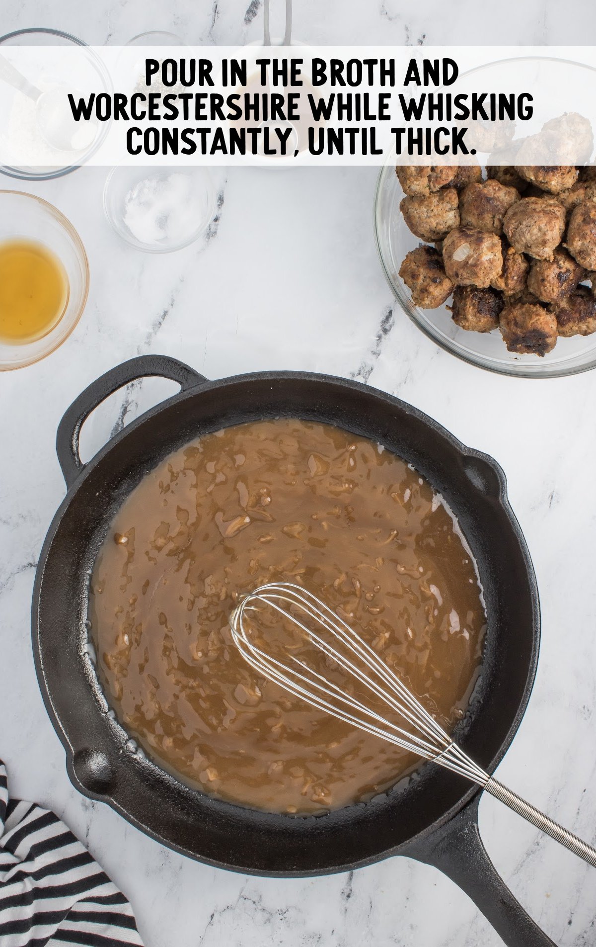 A skillet of prepared gravy with a whisk.