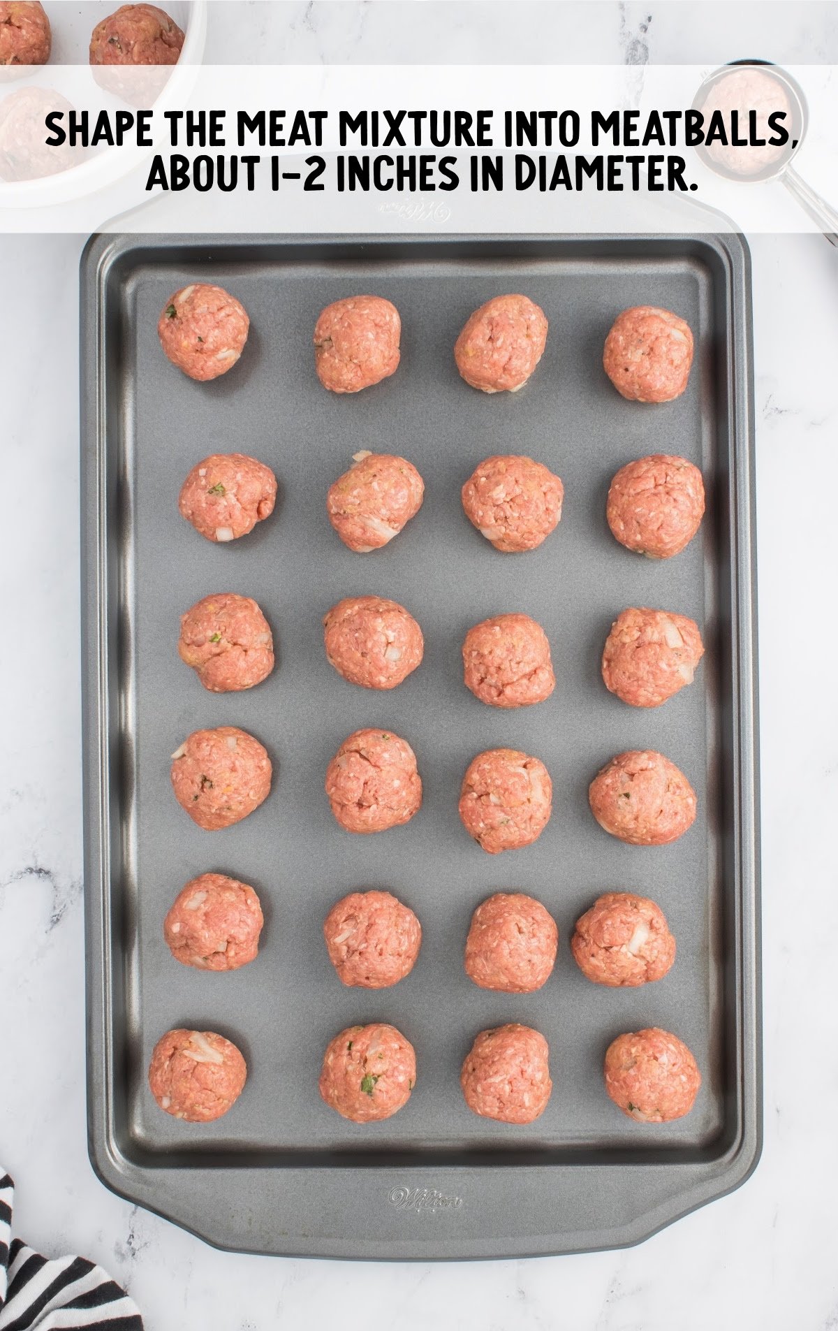 Uncooked rolled meatballs on a baking. sheet.