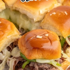 Philly cheesesteak sliders stacked on a board with melted cheese and shaved steak