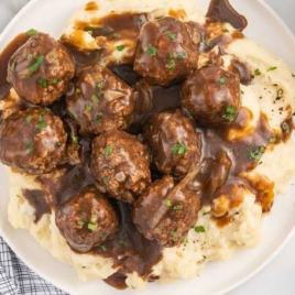 a plate of meatballs garnished with parsley and served over mashed potatoes