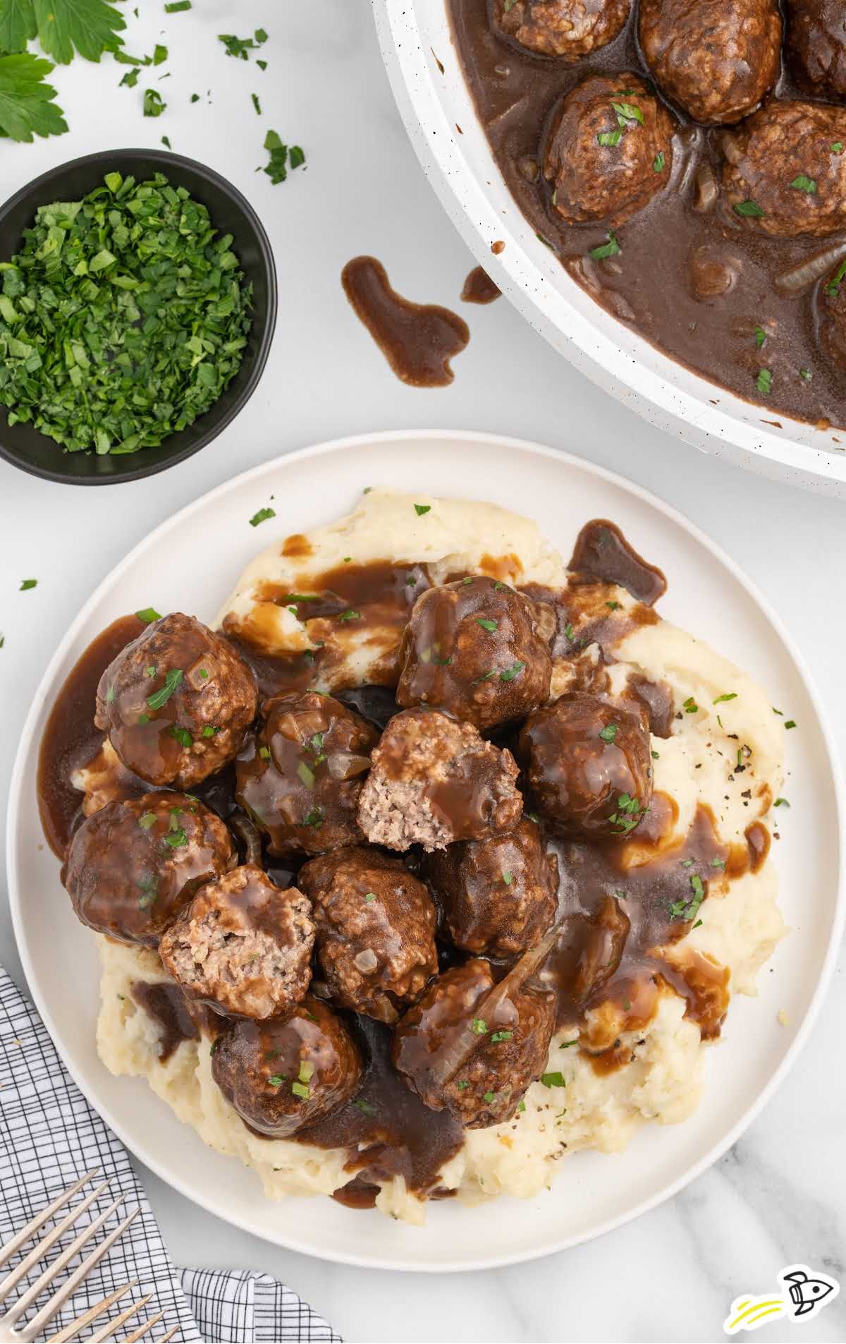 a plate of meatballs garnished with parsley and served over mashed potatoes