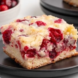 Close-up slice of cranberry cake highlighting the golden edges and vibrant cranberries throughout the cake.