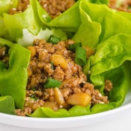 Close-up of chicken lettuce wraps served in butter lettuce leaves and garnished with green onions.