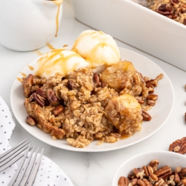 homemade banana crumble recipe on a plate with caramel sauce and a scoop of vanilla ice cream