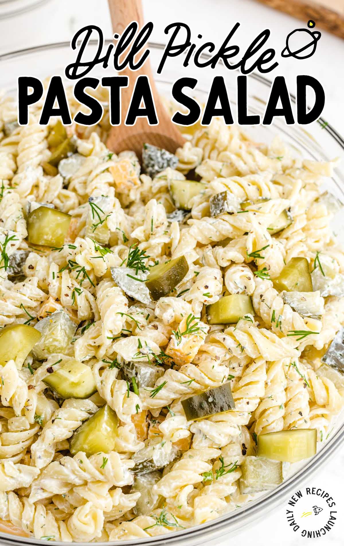 Text overlay reading “Dill Pickle Pasta Salad” above a close-up of creamy rotini pasta salad with dill and chunks of pickles.