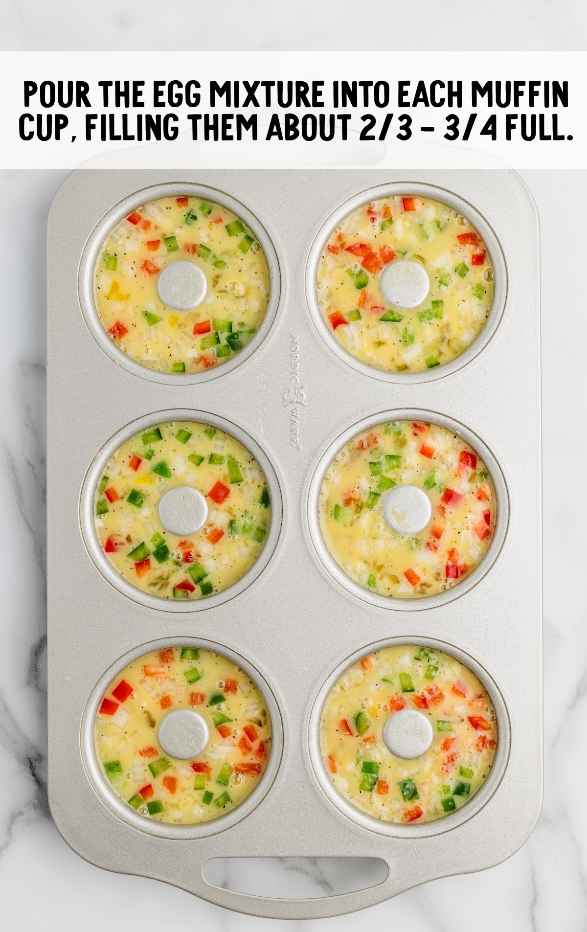 raw eggs, meat, and veggies in muffin tins ready to bake