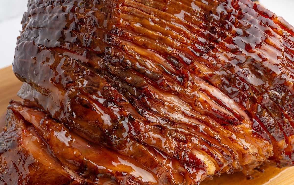 Thick, glossy honey glaze coating a spiral baked ham in a tight close-up shot.