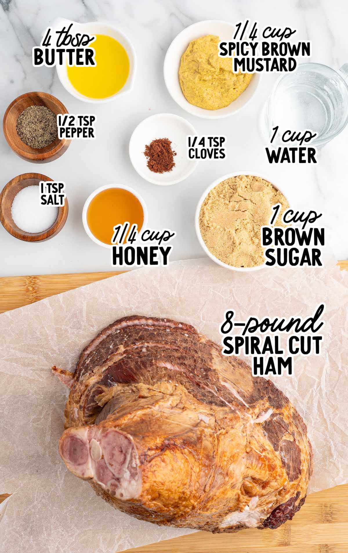 Ingredients for honey baked ham displayed on a counter, including spices, brown sugar, honey, mustard, butter, water, and an 8-pound spiral ham.