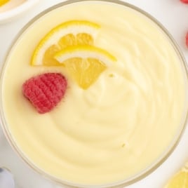 lemon custard in a bowl with fresh lemon and fresh berries