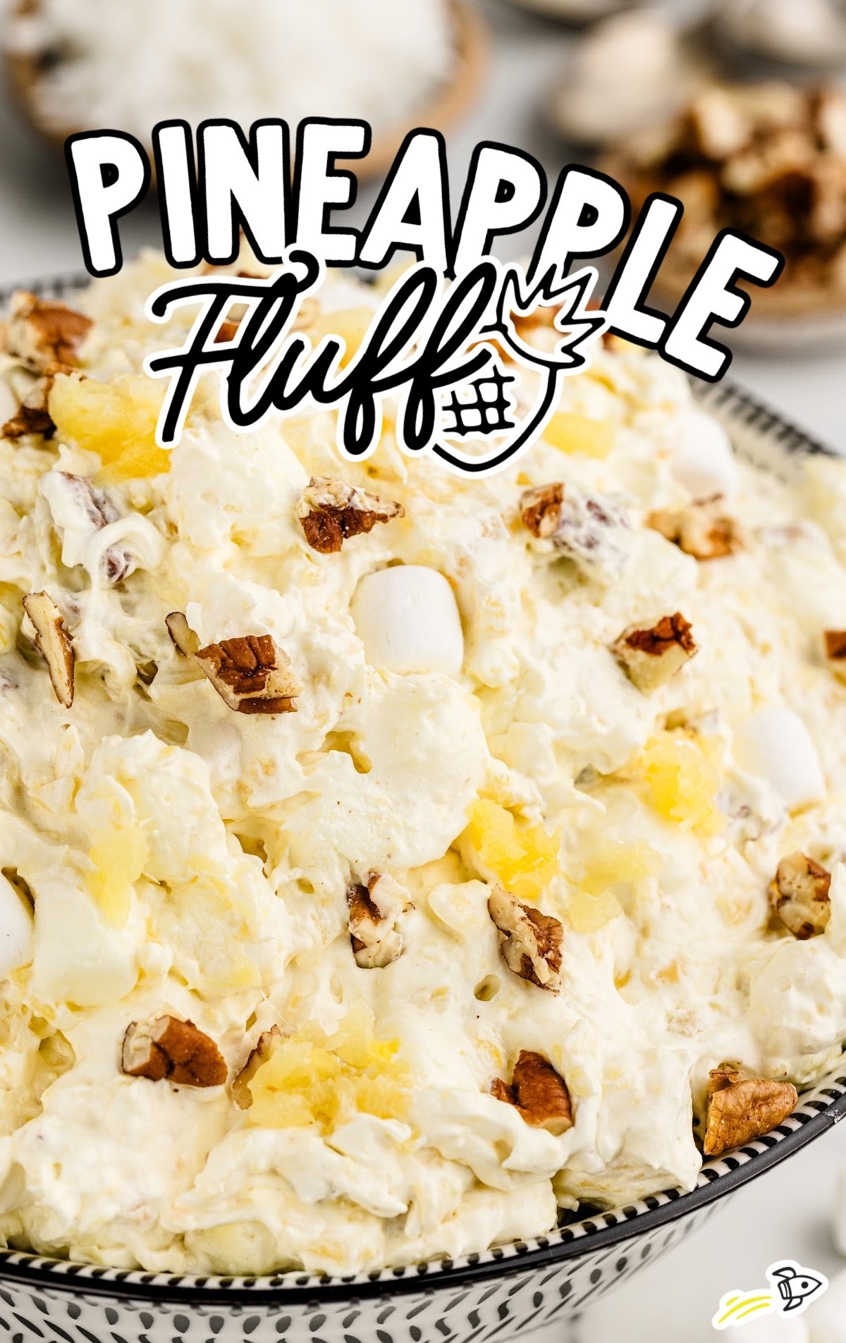 pineapple fluff dessert with nuts, pudding, cool whip, and marshmallows in a bowl ready to serve