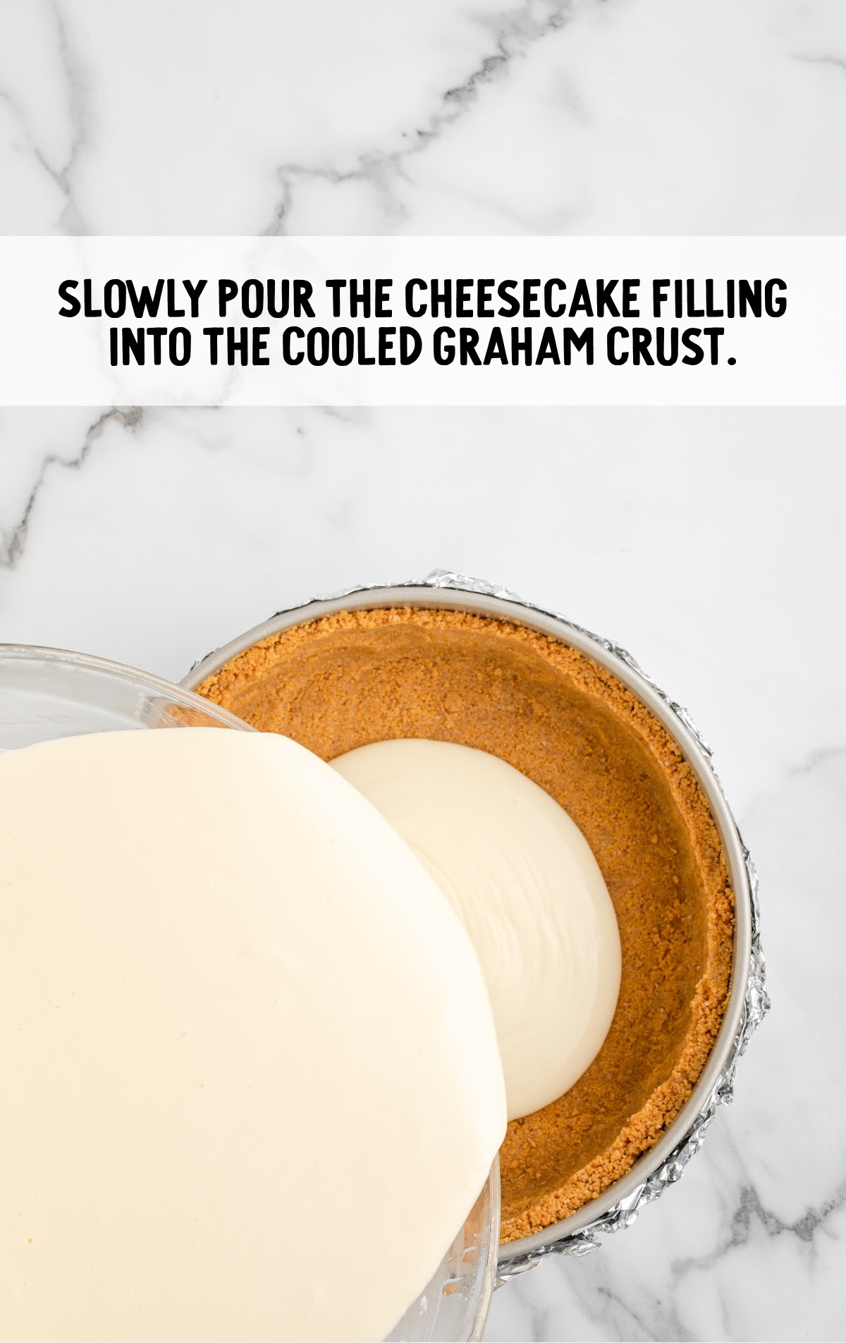 pouring cheesecake batter into a graham cracker crust before baking