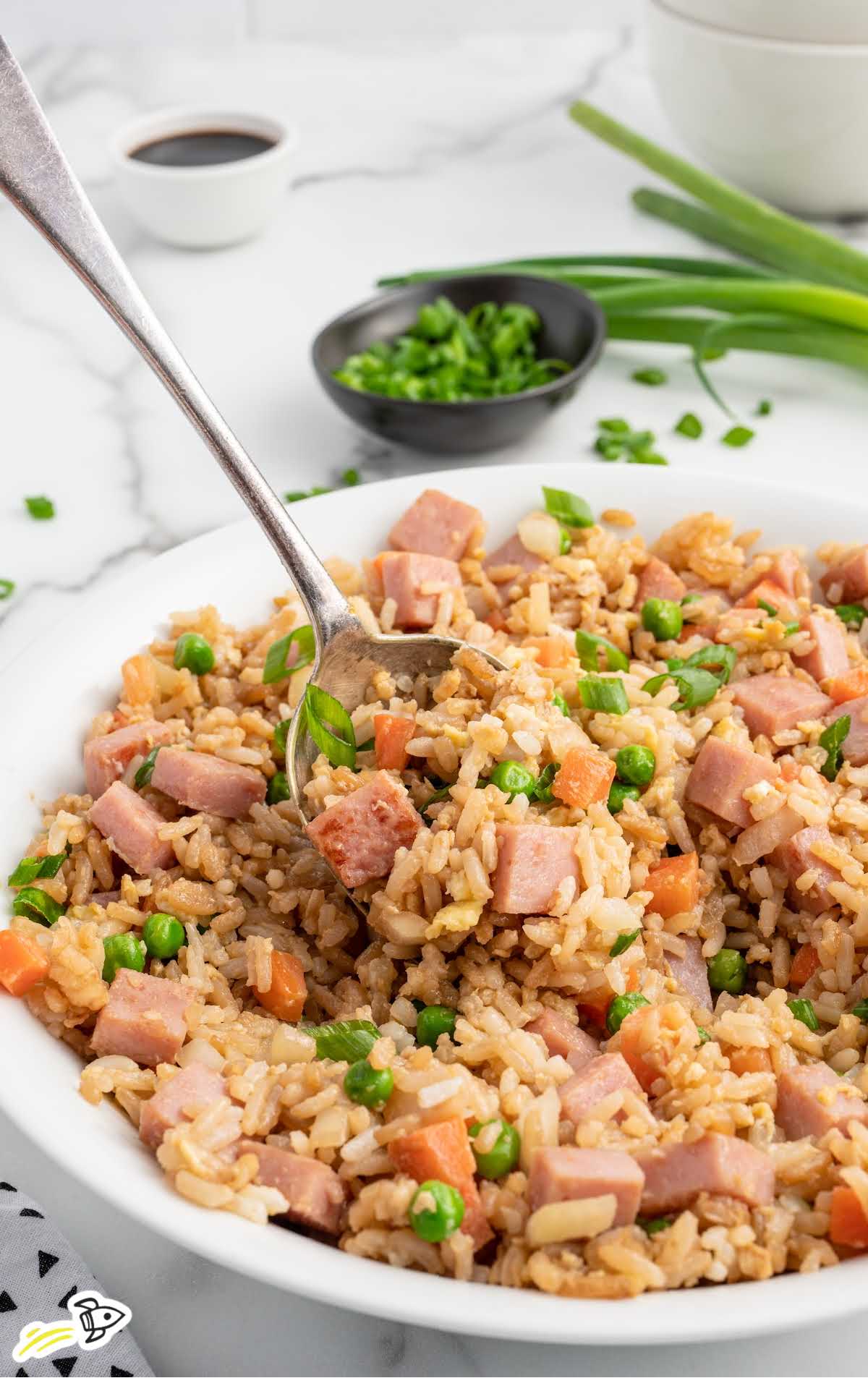 a bowl of ham fried rice with a spoon