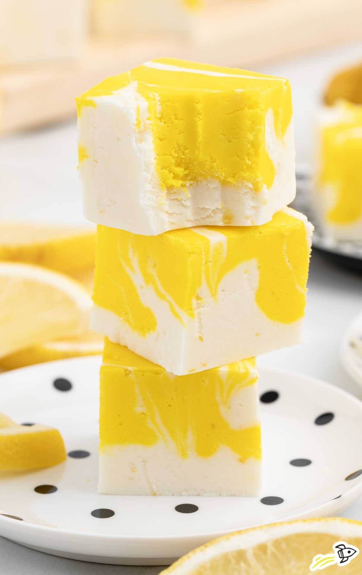 a bunch of Lemon Fudge bars stacked on top of each other on a plate