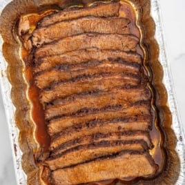 beef brisket sliced in an aluminum foil pan