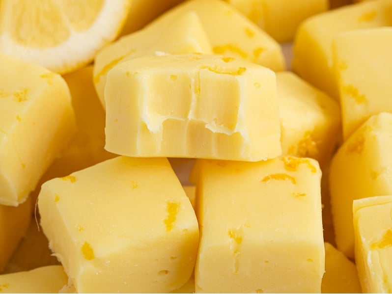 Several cubes of yellow butter are stacked closely together, resembling ingredients ready for a Lemon Fudge Recipe. One cube near the center even has bite marks in it.