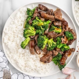 a plate of Air Fryer Beef and Broccoli topped with sesame seeds and served with white rice