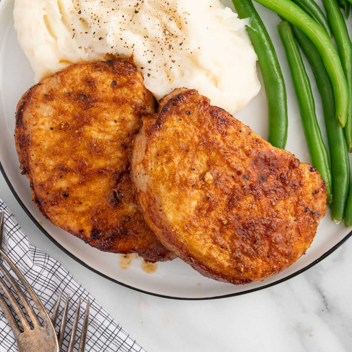 overhead shot of Pork Chops with mash potatoes and green beans on a plate