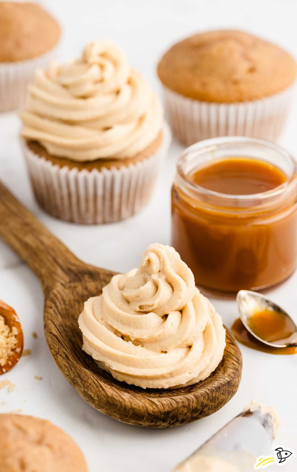 a close up shot of caramel icing on a wooden spoon