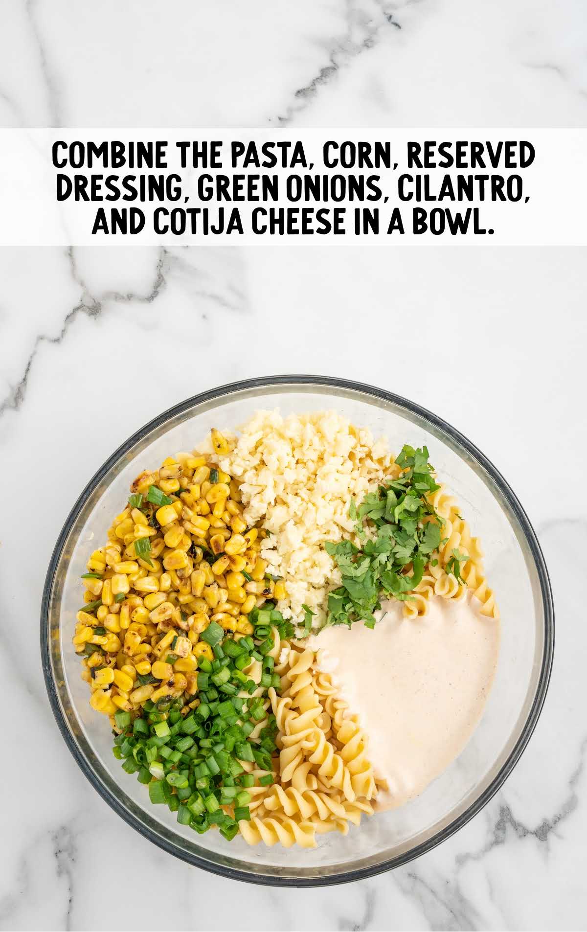 pasta, charred corn mixture, dressing, green onions, fresh cilantro, and cotija cheese added to a bowl