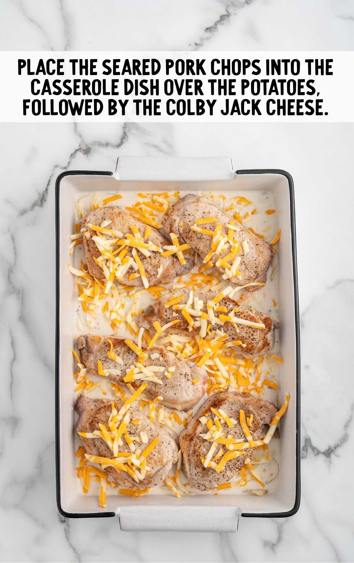 pork shops sprinkled with colby jack cheese in the casserole dish