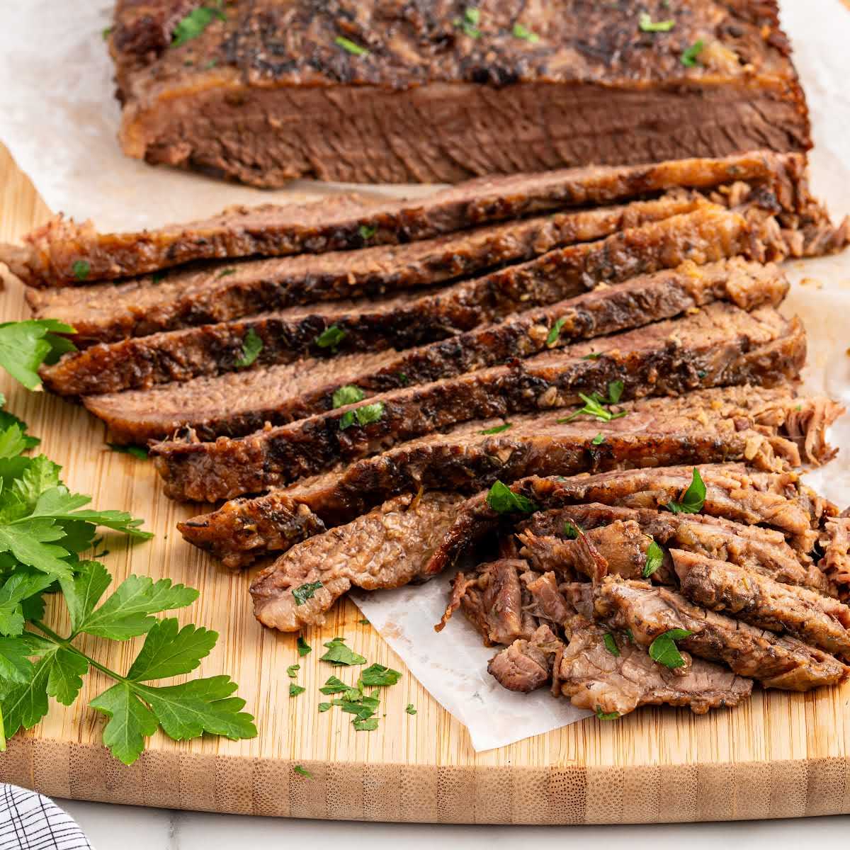 close up shot of slices of Slow Cooker Brisket on a wooden table