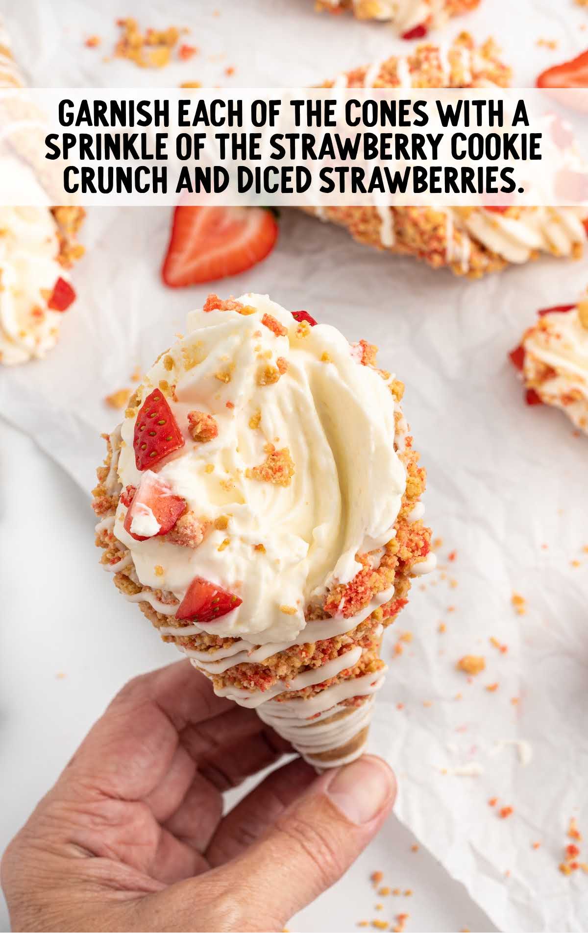 Strawberry Crunch Cheesecake Cones sprinkled with the reserved strawberry cookie crunch and a few freshly chopped strawberries