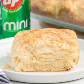 A 7up biscuit is on a side plate with a can of 7up behind it.