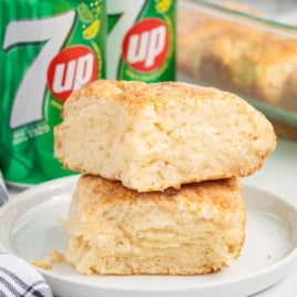 Two 7up Biscuits are resting on a white side plate beside a can of 7-UP.