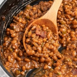 a skillet of Baked Beans with Ground Beef garnished with green onions