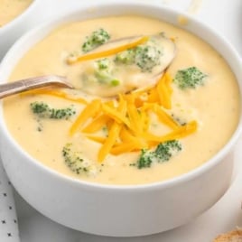 a bowl of Broccoli Cheese Soup topped with cheese with a spoon
